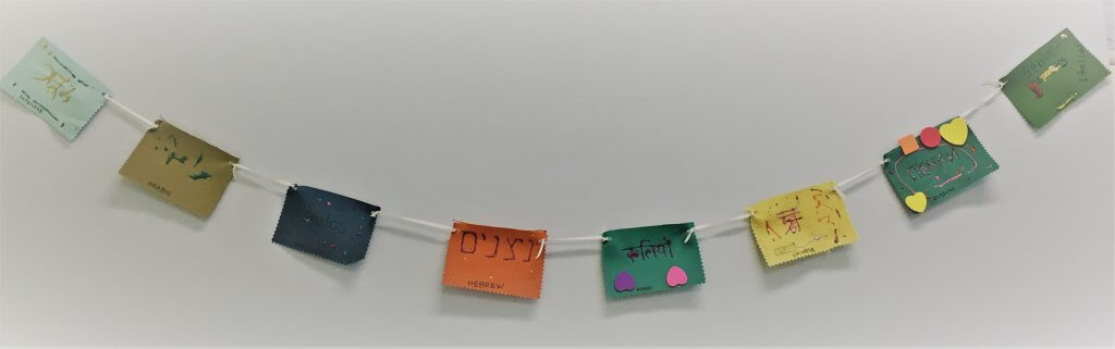 Kid-created "peace flag" that says "nitzanim" (buds) in 8 different languages.