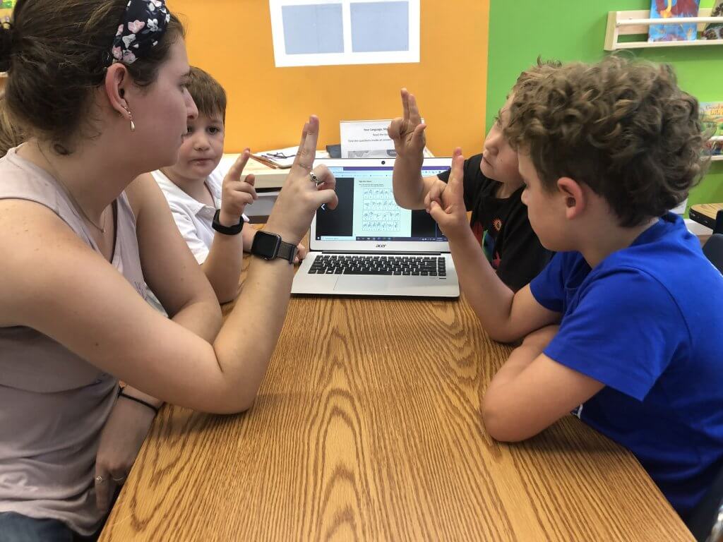 Noa helping students learn the manual alphabet from ASL