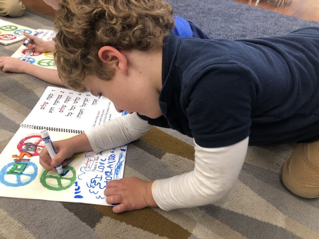 Kindergarten student reflecting on peace in his siddur (prayer book).