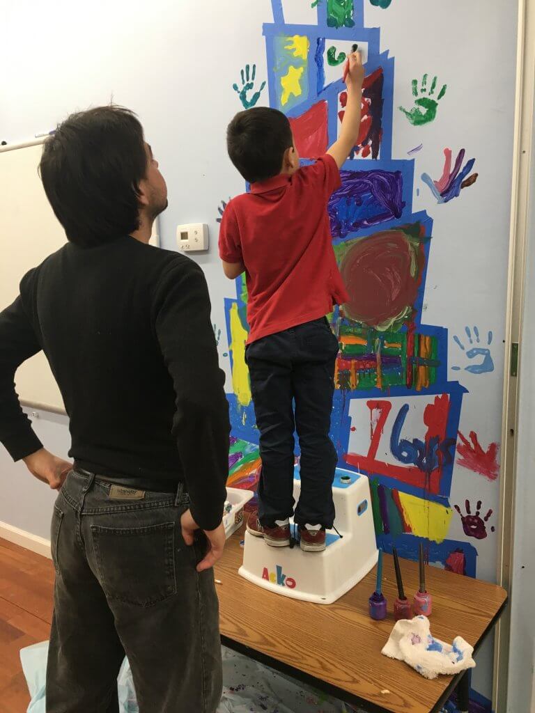 Joe stands watch as a student paints the brit background.