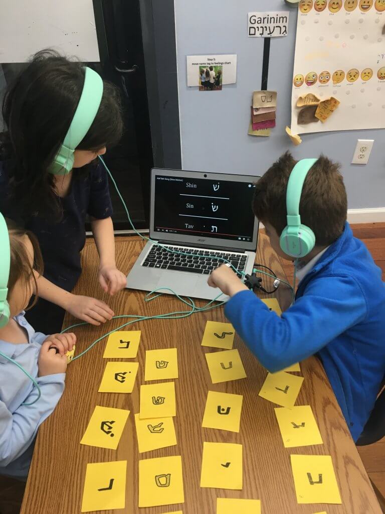 Three kiddos ordering the aleph-bet with the help of a recording.