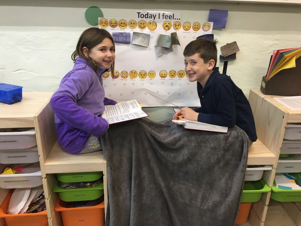 Two nitzanim (2nd-4th grade) kiddos get cozy to practice tefilah (prayer) together.