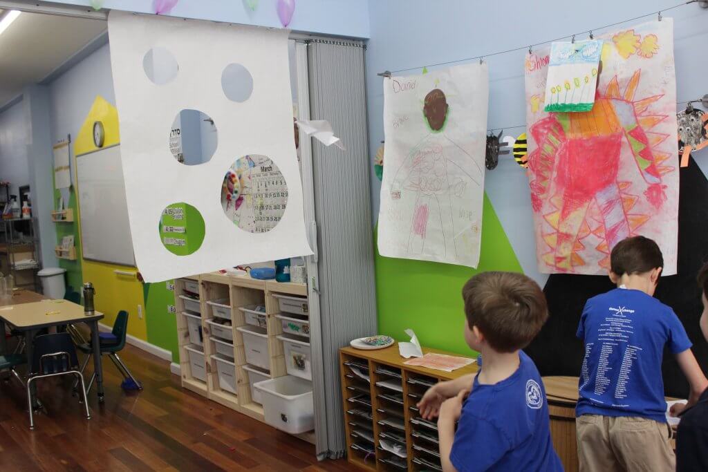 A 2nd grader throws a paper airplane through a target.