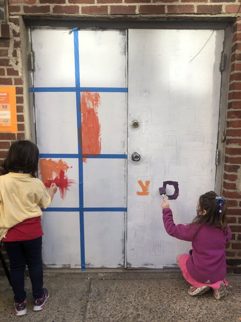 Two kindergarteners paint the doors to Makom on Ionic Street.