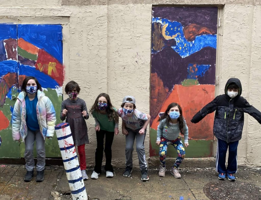 Third and Forth graders jumping in front of their outdoor paintings.