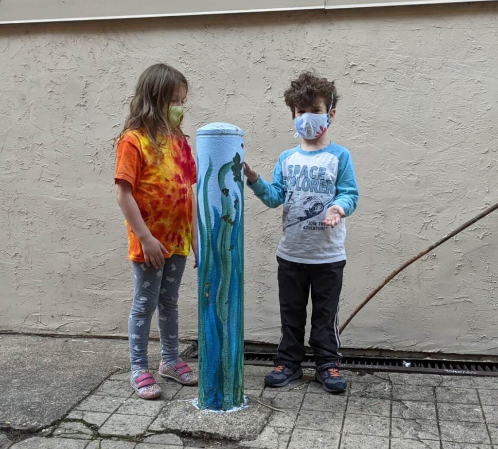 Two first graders standing outside next to a pole