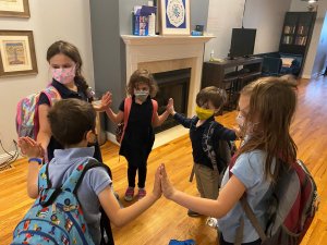 kiddos in a circle touching hands between the transition from school to Stl in response to the prompt "make a shape" 